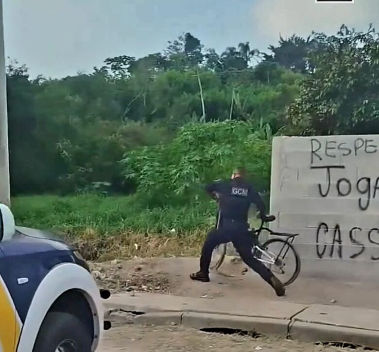 Captura de tela do vídeo mostra momento em que o GCM está jogando a bicicleta do entregador no córrego