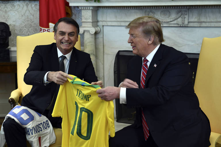 Os presidentes Jair Bolsonaro e Donald Trump trocam camisas de futebol durante encontro na Casa Branca